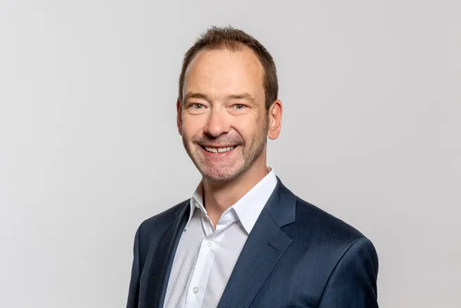 Das Porträt zeigt Prof. Andre Borrmann, der in die Kamera lächelt. Er trägt ein blaues Jackett mit einem weißen Hemd darunter.